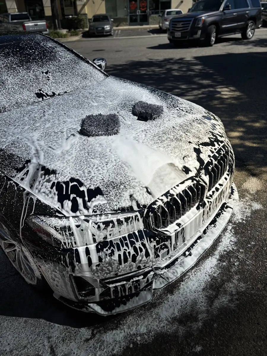 Thick foam clinging to a BMW grille mid-wash