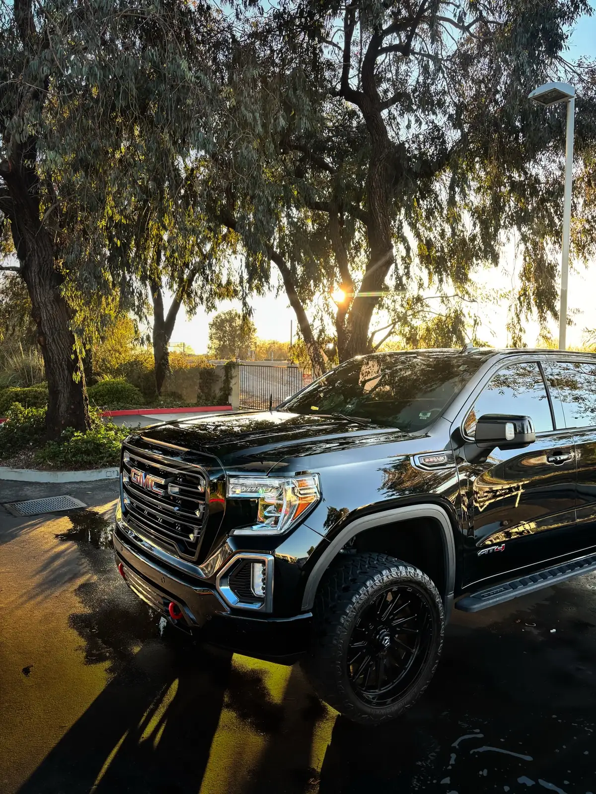 Black GMC Sierra AT4 glowing in golden-hour light after a detail